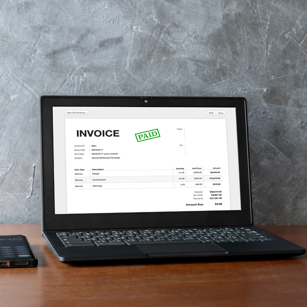 Laptop showing invoice with a green PAID stamp